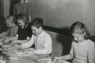 876621 Portret van enkele kinderen die tijdschriften 'De Stad Gods' aan het vouwen zijn voor verdere distributie, in ...